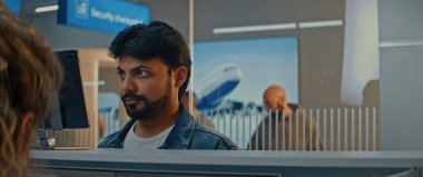 Havaalanı kontrol gişesi: Hintli Adam Yüz Tanıma Taramasıyla Biyometrik Verileri Doğrulayarak Havayolu Ajanı 'na Belge ve Uçak Biletleri Veriyor. Uluslararası Havalimanı Terminalinde Pasaport Denetimi.