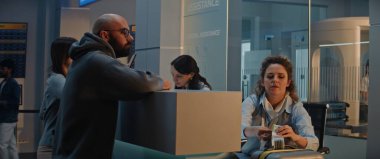 Havaalanı sayacındaki çeşitli yolcular: Kadın Havayolu check-in görevlisi Erkek Bagajını kontrol ediyor, Uçuş Bavuluna Barkod etiketi koyuyor. Uluslararası Havaalanı Terminalinde Güvenlik Kontrol Noktası.