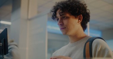 Havaalanı check-in gişesindeki çeşitli yolcular: Uluslararası Havalimanı Terminali 'nde Kimlik Verisini Yüz Tanıma Taramasıyla Doğrulayan, Pasaport Kontrolü sırasında Havayolu İşçisiyle Konuşan Genç Adam.