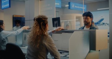 Check-in Counter 'daki çok ırklı yolcular: Kadın Havayolu Ajanları Belge ve Uçak Biletlerini Kabul Ediyor, Bilgisayarlardaki Biyometrik Verileri Kontrol Ediyor. Uluslararası Havalimanı Terminalinde Pasaport Kontrolü.