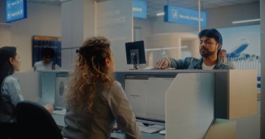 Check-in Counter 'daki çok ırklı yolcular: Kadın Havayolu Ajanları Belge ve Uçak Biletlerini Kabul Ediyor, Bilgisayarlardaki Biyometrik Verileri Kontrol Ediyor. Uluslararası Havalimanı Terminalinde Pasaport Kontrolü.
