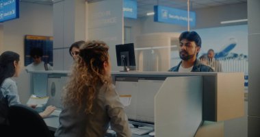 Check-in Counter 'daki çok ırklı yolcular: Kadın Havayolu Ajanları Belge ve Uçak Biletlerini Kabul Ediyor, Bilgisayarlardaki Biyometrik Verileri Kontrol Ediyor. Uluslararası Havalimanı Terminalinde Pasaport Kontrolü.