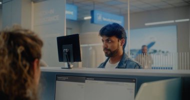 Havaalanı kontrol gişesi: Hintli Adam Yüz Tanıma Taramasıyla Biyometrik Verileri Doğrulayarak Havayolu Ajanı 'na Belge ve Uçak Biletleri Veriyor. Uluslararası Havalimanı Terminalinde Pasaport Denetimi.