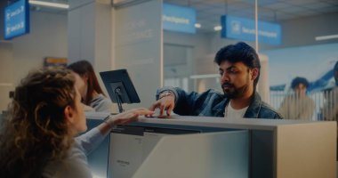 Havaalanı kontrol gişesi: Kadın havayolu işçisi Bilgisayarda Yolcu Kimlik Verilerini Denetliyor, Belgeler ve Kızılderili Adam 'a Uçuş Kartı Veriyor. Uluslararası Havalimanı Terminalinde Pasaport Denetimi.