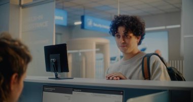 Havaalanı kontrol gişesi: Genç Adam Kimlik Tanıma Taramasıyla Kimlik Verilerini Doğrulayarak Havayolu İşçisine Belge Veriyor ve Uçak Biletini Veriyor. Uluslararası Havalimanı Terminalinde Pasaport Denetimi.