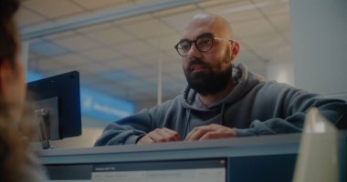 Havaalanı kayıt gişesindeki genç adam: Bayan Havayolu Ajanı Belgeleri Kontrol Ediyor, Yolcuya Pasaport ve Uçuş Kartı Veriyor. Uluslararası Havaalanı Terminalinde Müşteri Hizmetleri ve Pasaport Denetimi.