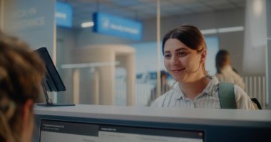 Havaalanı kontrol gişesi: Parmak izi taraması yapan yolcu. Bayan Havayolu İşçisi Bilgisayarda Kişisel Kimlik Verilerini Kontrol Ediyor, Belgeler Veriyor ve Kadına Giriş Kartı Veriyor. Uluslararası Havaalanı Terminali