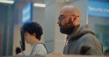 Check-in sayacındaki yolcular: Pasaport ve Uçuş Biletini Hava Yolları İşçisine Veren Adam, Parmak izi ve Yüz Tanıma ile Kişisel Kimlik Verisini Doğrulama. Havaalanı Terminalinde Belge Denetimi.