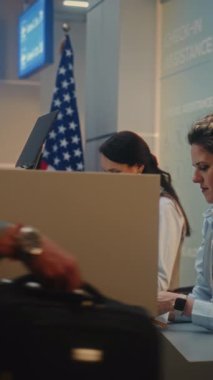 Havaalanındaki check-in sayacı: Hintli Adam Havayolu İşçisine Yatılı Belge Veriyor, Bagaj Denetimi için Bavulu Yerleştiriyor, Kimlik Biyometrik Parmak izi Taraması için Parmak İzini Dokunma Ekranına Veriyor. Dikey Çekim