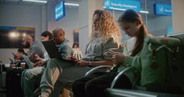 Kalabalık Uluslararası Havaalanı Terminali: Laptop 'ta Çalışan Kadın, E-posta Gönderiyor. Çeşitli İnsanlar, Yolcular, Uçak Hat Biniş Salonunda oturan, Uçak Uçuşunu Bekleyen, Telefonları Kullanan.