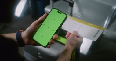 Havaalanı Terminali: Havayolu Hub Lounge 'da oturan adam, Yeşil Chroma Anahtarlı Telefon ile Uçak Biletini Tarıyor Mock Up. Uygulama Arayüzü için Yer Tutucu ile Görüntü Şablonu.