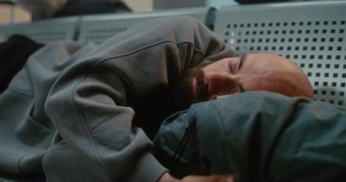 Kalabalık Uluslararası Havalimanı Terminali: Sırt çantalı Yorgun Adam 'ın Kapanışı Hava Yolları Merkezinde Koltuklarda Uyuyor. Gecikmiş Uçak Uçuşunu Bekleyen Yolcu. Turizm ve Seyahat.