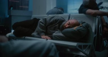 Kalabalık Uluslararası Havalimanı Terminali: Yorgun Adam Sırt çantasında Uyuyor Gece Havalimanı 'nın Yatılı Salonunda. Çeşitli İnsanlar ve Yolcular Gecikmiş Uçak Uçuşunu Bekliyor.