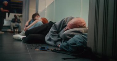 Kalabalık Uluslararası Havalimanı Terminali: Yorgun Adam Havayolu Merkezinin Kalkış Salonunda Uyuyor. Çeşitli İnsanlar ve Yolcular Gecikmiş Uçak Uçuşunu Bekliyor. Turizm ve Seyahat.