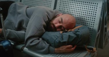 Kalabalık Uluslararası Havalimanı Terminali: Sırt çantalı Yorgun Adam 'ın Kapanışı Hava Yolları Merkezinde Koltuklarda Uyuyor. Gecikmiş Uçak Uçuşunu Bekleyen Yolcu. Turizm ve Seyahat.