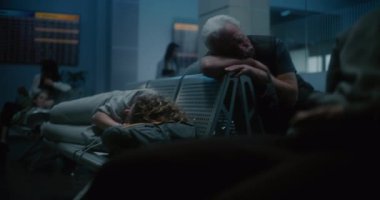 Kalabalık Uluslararası Havaalanı Terminali: Yorgun Kadın Gece Havalimanı 'nın Kalkış Salonunda Sırt Sırtında Uyuyor. Yorgun İnsanlar ve Yolcular Gecikmiş Uçak Uçuşunu Bekliyor.