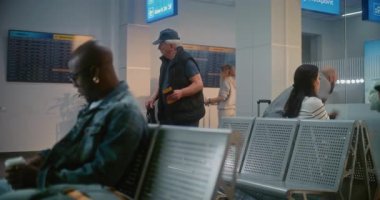 Kalabalık Uluslararası Havaalanı Terminali: Afro-Amerikan Genç Adam Oturuyor, Uçak Uçuşunu Bekliyor, Seyahate Çıkıyor. Çok Irklı İnsanlar ve Yolcular Hava Yolları Merkezinin Kalkış Salonunda.