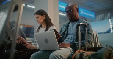 Kalabalık Uluslararası Havaalanı Terminali: Laptop 'ta Uzaktan Çalışan Afrikalı Amerikalı Adam. Yolcular, Dijital Gadget kullanarak, Uçak İndirme Merkezi Biniş Salonunda, Uçak Uçuşunu Bekliyor..