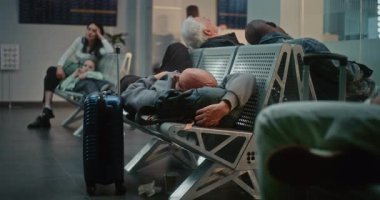 Kalabalık Uluslararası Havaalanı Terminali: Yorgun Adam ve Uçak İnbotu 'nun Yatılı Salonu' nda Koltuklarda Uyuyor. Çeşitli İnsanlar ve Yolcular Gecikmeli Uçuşu Bekliyor. Dolly Yakınlaştır