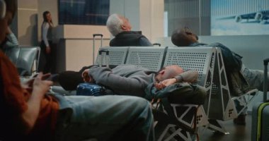 Kalabalık Uluslararası Havaalanı Terminali: Yorgun Adam ve Uçak İnbotu 'nun Yatılı Salonu' nda Koltuklarda Uyuyor. Çeşitli İnsanlar ve Yolcular Gecikmeli Uçuşu Bekliyor. Turizm ve Seyahat