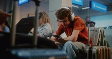 Kalabalık Uluslararası Havaalanı Terminali: Erkek ve Kız, Genç Kardeşler Akıllı Telefon Kullanıyor, Atıştırmalık yiyor, Seyahat İçin Uçuşu Bekliyor. Farklı Yolcular Hava Yolları Merkezinin Kalkış Salonunda Oturuyorlar.