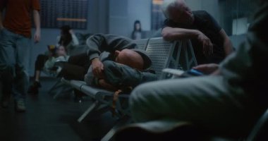 Kalabalık Uluslararası Havaalanı Terminali: Yorgun Adam Gece Havalimanı 'nın Kalkış Salonunda Sırt çantasında Uyuyor. Çeşitli Yolcular ve Gezginler Gecikmiş Uçak Uçuşunu Bekliyor.