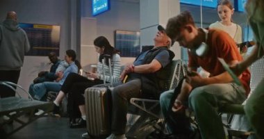 Kalabalık Uluslararası Havaalanı Terminali: Uçuşlar ve Seyahatler için Yolcu Kapısına Yürüyen çeşitli Yolcular. Bavullu kıdemli adam havayolu merkezinin kalkış salonunda koltukta oturuyor..