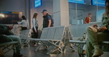 Kalabalık Uluslararası Havalimanı Terminali 'ndeki Çeşitli İnsanlar: Bavulu, Belgeleri ve Biniş Geçidi olan Kıdemli Adam Pasaport Kontrolünden Sonra Hava Yolları İnbotu Salonunda Oturuyor, Uçuşu Bekliyor.