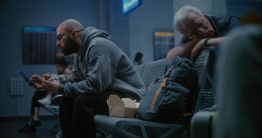 Gece Havayolları İnbotu Biniş Salonu: İnsan Fast Food yiyor ve Uluslararası Kalabalık Havaalanı Terminalinde Akıllı Telefon Kullanıyor. Yorgun Yolcular ve Gezginler Gecikmiş Uçak Uçuşunu Bekliyor