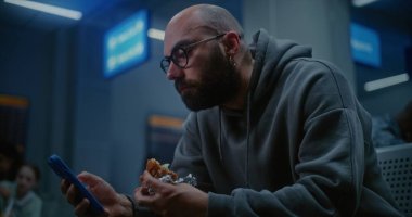 Gece Havayolları İnbotu 'nun Yatılı Salonu İnsan Yiyen Burger ve Kaydıran Akıllı Telefon. Kalabalık Uluslararası Havaalanı Terminalinde oturan Yolcu, Tatil Uçuşu için Gecikmiş Uçak Bekliyor.