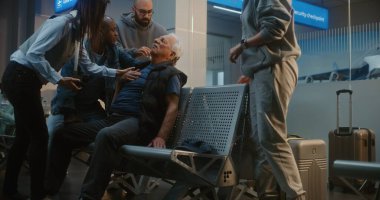 Kalabalık Uluslararası Havalimanı Terminali: Yaşlı Adam Kalp krizi geçiriyor, Infarction in Inarding Lounge of Airline Hub. Kıdemli Yolcuya Yardım Eden Çeşitli İnsanlar, Havaalanı İşçisi Tıbbi Yardım Çağrısı.