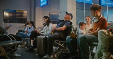 Kalabalık Uluslararası Havaalanı Terminali: Çeşitli İnsanlar ve Yolcular Gecikmeli Uçuşu Bekliyor, Seyahate Çıkıyor. Bavullu yaşlı adam, havayolu merkezinin bekleme salonunda, koltukta oturuyor..