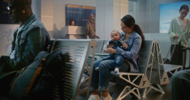 Kalabalık Uluslararası Havaalanı Terminali: Laptop kullanan Afrikalı Amerikalı Adam, Küçük Bebekle Oturan Kadın. Çeşitli Gezginler, Yolcular, Uçak Kalkış Salonunda Uçak Uçuşunu Bekliyor.