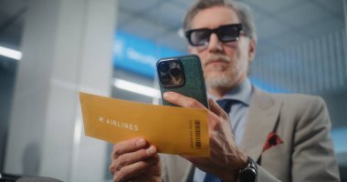 Havaalanı Terminali: Akıllı Telefon kullanarak, Bilgi Denetleyerek Başarılı Girişimci Uçak Tarayıcı Biletleri. VIP Ayrılış Salonunda Uçağı Bekleyen İşadamı. E-Bilet Teknolojisi. Görüntüyü Kapat.