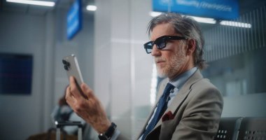 Havaalanı Terminali: Başarılı İşadamı Smartphone 'da İş Ortağıyla Konuşuyor, Video Call, Oturma Salonu. Girişimci Uçak Uçuşunu Bekliyor, Seyahate Çıkıyor. Ortam Kapalı.