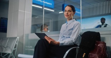 Havaalanı Terminali: Dijital Tablet Kullanmakta, E-İş Yapmakta, Uzaktan Çalışmakta, Kameraya Bakmakta Başarılı İş Kadını. Girişimci Seyahate Çıkıyor, Kalkış Salonunda Uçuş Bekliyor. Doli Vuruşu.