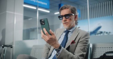 Havaalanı Terminali: Başarılı Girişimci Akıllı Telefondan Yatırımcıyla Konuşuyor, Video Sohbet, Kahve İçme. İş adamı kalkış salonunda uçuşu bekliyor, iş gezisine çıkıyor. Ortam Kapalı.