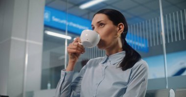 Uluslararası Havaalanı Terminali: VIP Ayrılış Salonu 'nda oturan ve İçen Kadın Girişimci. Başarılı bir iş kadını uçak bileti bekliyor, iş seyahatine çıkıyor. Görüntüyü Kapat.