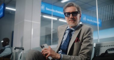 Havaalanı Terminali: Akıllı Telefon Kullanan ve Kahve İçen Olgun İşadamı, Kameraya Bakıyor. Girişimci, Bavul Ayrılış Salonunda Uçuş Bekliyor, İş Gezisine Çıkıyor. Doli Vuruşu.