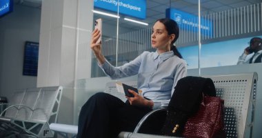 Havaalanı Terminali: Akıllı Telefondan Yatırımcıyla Konuşan Kadın Girişimci, Video Sohbeti. Başarılı bir iş kadını kalkış salonunda uçak bileti bekliyor, iş seyahatine çıkıyor. Doli Vuruşu.