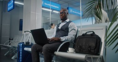 Havaalanı Terminali: Laptop kullanan ve kahve içen Afrikalı Amerikalı Girişimci, e-ticaret yapıyor. İş adamı Uzaktan Çalışmalar Kalkış Salonunda Uçuşunu Bekliyor, İş Gezisine Gidiyor. Doli Vuruşu.