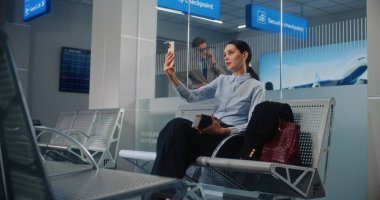 Havaalanı Terminali: Başarılı İş Kadını Akıllı Telefon 'da İş Ortağıyla Konuşuyor, Video Çağrısı, Kalkış Salonunda Uçak Bekliyor. Bayan Girişimci Seyahate Çıkıyor. Sabit Çekim.