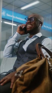 Havaalanı Terminali: Başarılı Afrikalı Amerikalı İş Adamı Cep Telefonu 'ndan İş Ortağına Konuşuyor. Girişimci, Airline Hub 'ın Kalkış Salonunda Uçuşu Bekliyor, Seyahate Çıkıyor. Dikey Çekim.