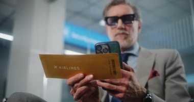 Havaalanı Terminali: Başarılı İşadamı Tarayıcı Uçuş Bilgilerini Kontrol ederek Akıllı Telefon kullanarak Uçuş Geçidi. Girişimci VIP Ayrılış Salonunda oturuyor. E-Bilet Teknolojisi. Rack Odağını Kapat.