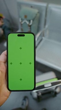 Kalabalık Havalimanı Terminali: POV Man, Airline Hub Lounge 'da duruyor, Smartphone Green Chroma Key Mockup ile kayıyor. Sosyal Medya İçeriği 'nin yer sahibi. Birinci Şahıs Görünümü. Dikey Çekim.