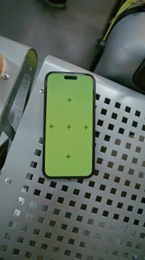 Havaalanı Terminalindeki Havayolu Hub Lounge: Yeşil Kroma Anahtarlı Akıllı Telefon Mockup Kahve ve Bavul 'un yanındaki koltukta uzanıyor. Sosyal Medya İçeriği için Yer Tutucu ile Görüntü Şablonu. Dikey Çekim.