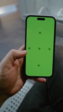 Kalabalık Havaalanı Terminali: Havayolu Hub Lounge 'da oturan adam, Green Chroma Key Mock Up ile cep telefonu kullanıyor. İş Reklamcılığı için video şablonu. Birinci Şahıs Görünümü. Dikey Çekim.