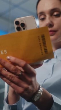 Havaalanı Terminali: İş kadını Tarayıcı Uçuş Bilgilerini Akıllı Telefon kullanarak kontrol ediyor. Kadın Girişimci VIP Ayrılış Salonu 'nda oturuyor. E-Bilet Teknolojisi. Dikey Görüntüyü Kapat.