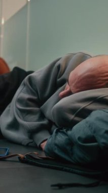 Kalabalık Uluslararası Havaalanı Terminali: Yorgun Adam Gidiş Salonunda Yerde Uyuyor. Çeşitli İnsanlar ve Yolcular Gecikmiş Uçak Uçuşunu Bekliyor. Turizm ve Seyahat. Dikey Çekim.