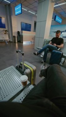 Kalabalık Havalimanı Terminali: POV Yolcu Uçan Daire 'nin Yatılı Salonunda Oturuyor, Kağıt Kupadan Kahve İçiyor. Turistler uçuşu bekliyor, tatile çıkıyorlar. Birinci Şahıs Görünümü. Dikey Çekim